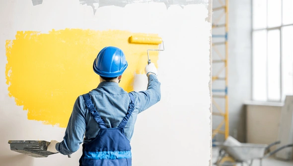 Professional painter applying fresh paint to the wall of an office for a modern look.